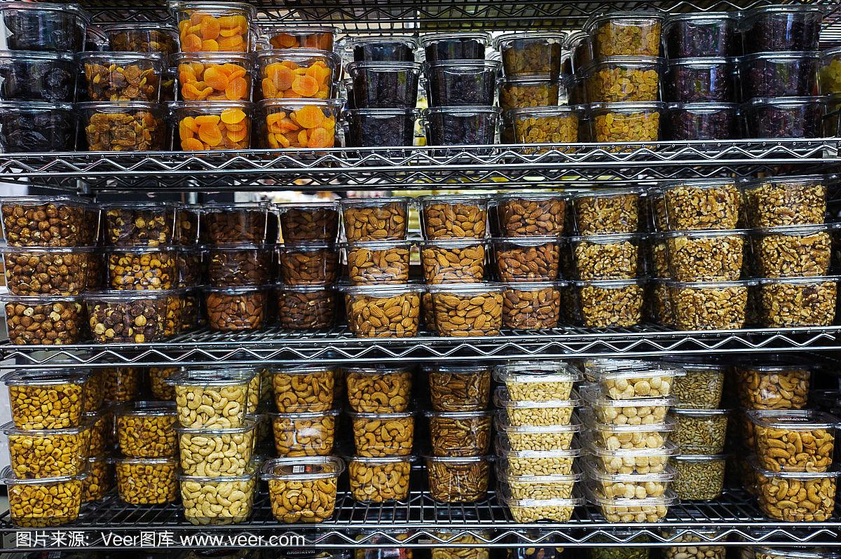各种干果和坚果装在塑料容器里塞满了超市的金属货架